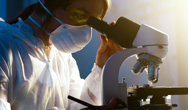 lab technician looking through a microscope